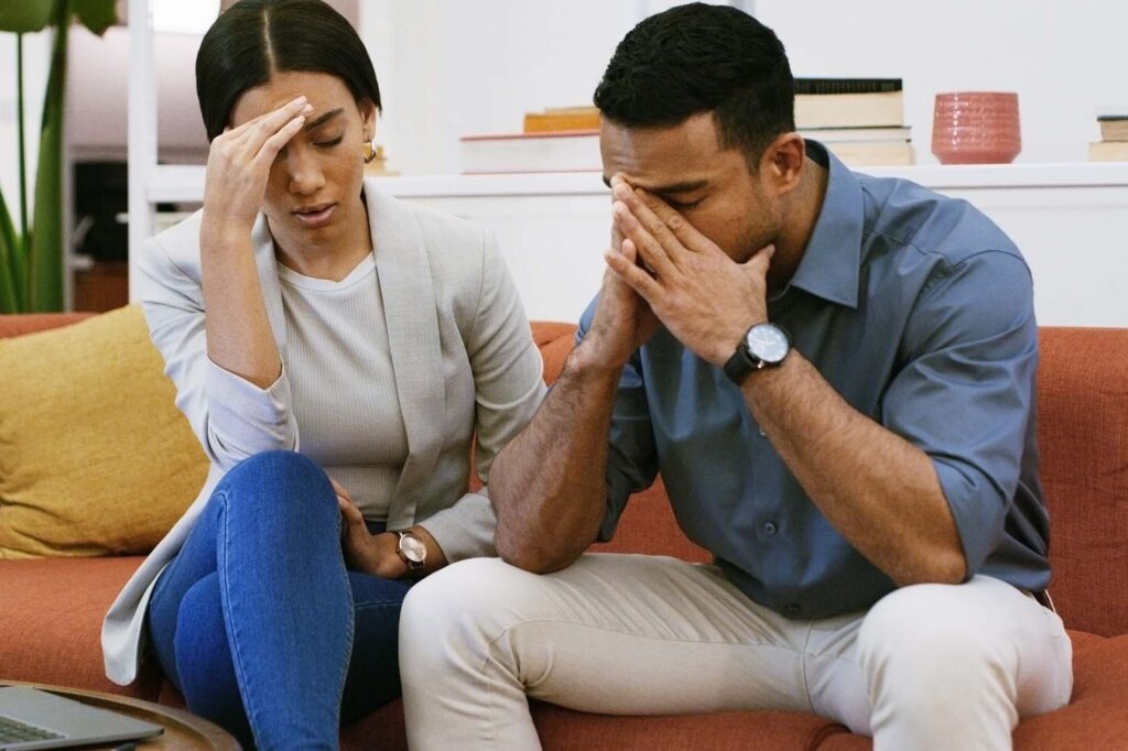 Sofa, business people and stress with laptop for debt, company bankruptcy or mistake. Man, woman or colleagues in office with anxiety, budget project and frustrated for deadline or financial crisis