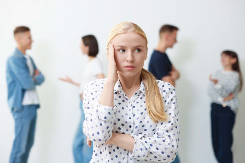 Young woman feeling uncomfortable among people indoors, selective focus